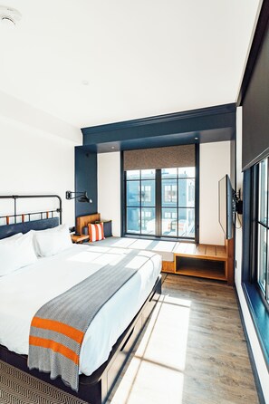 A modern hotel room with a large bed, a seating area with a view, and a television.