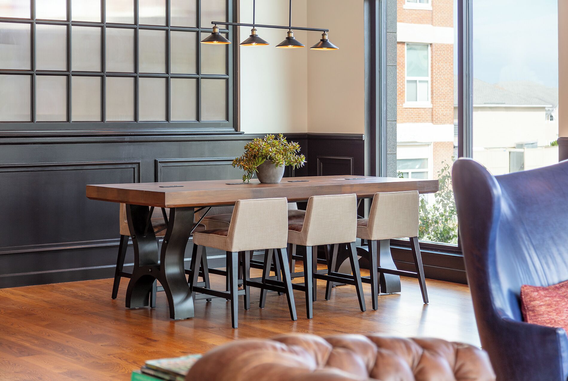Un comedor con una mesa de madera, cuatro sillas y una planta en maceta.