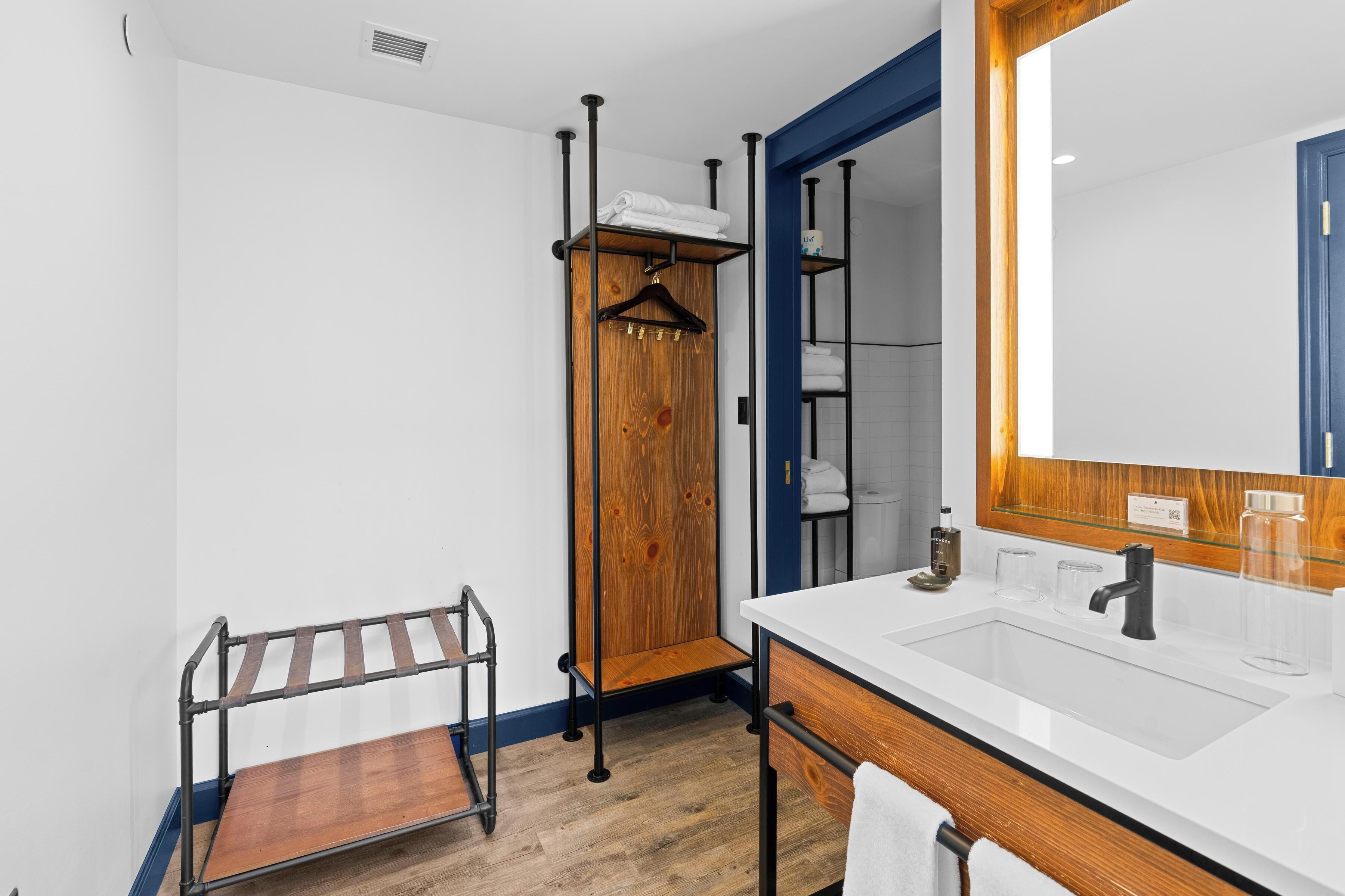 Ein modernes Badezimmer mit Waschbecken, Holz-Waschtisch und Handtuchhalter.