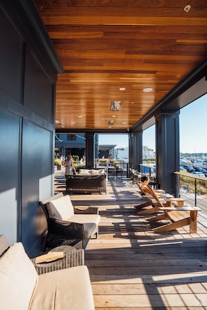 An outdoor patio with wicker furniture, a wooden ceiling, and a view of the marina.