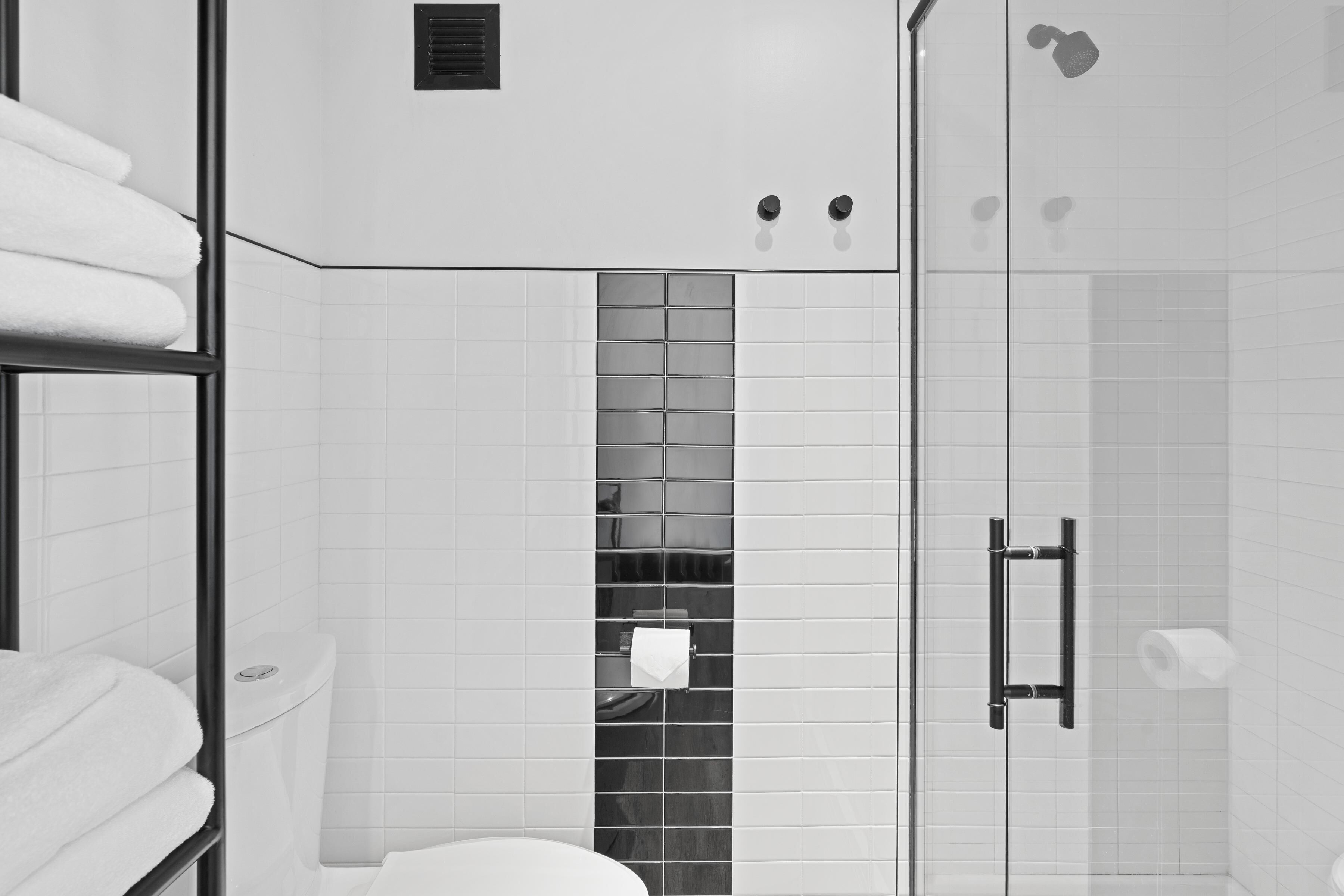 A modern bathroom with a glass shower enclosure, a toilet, and a towel rack.