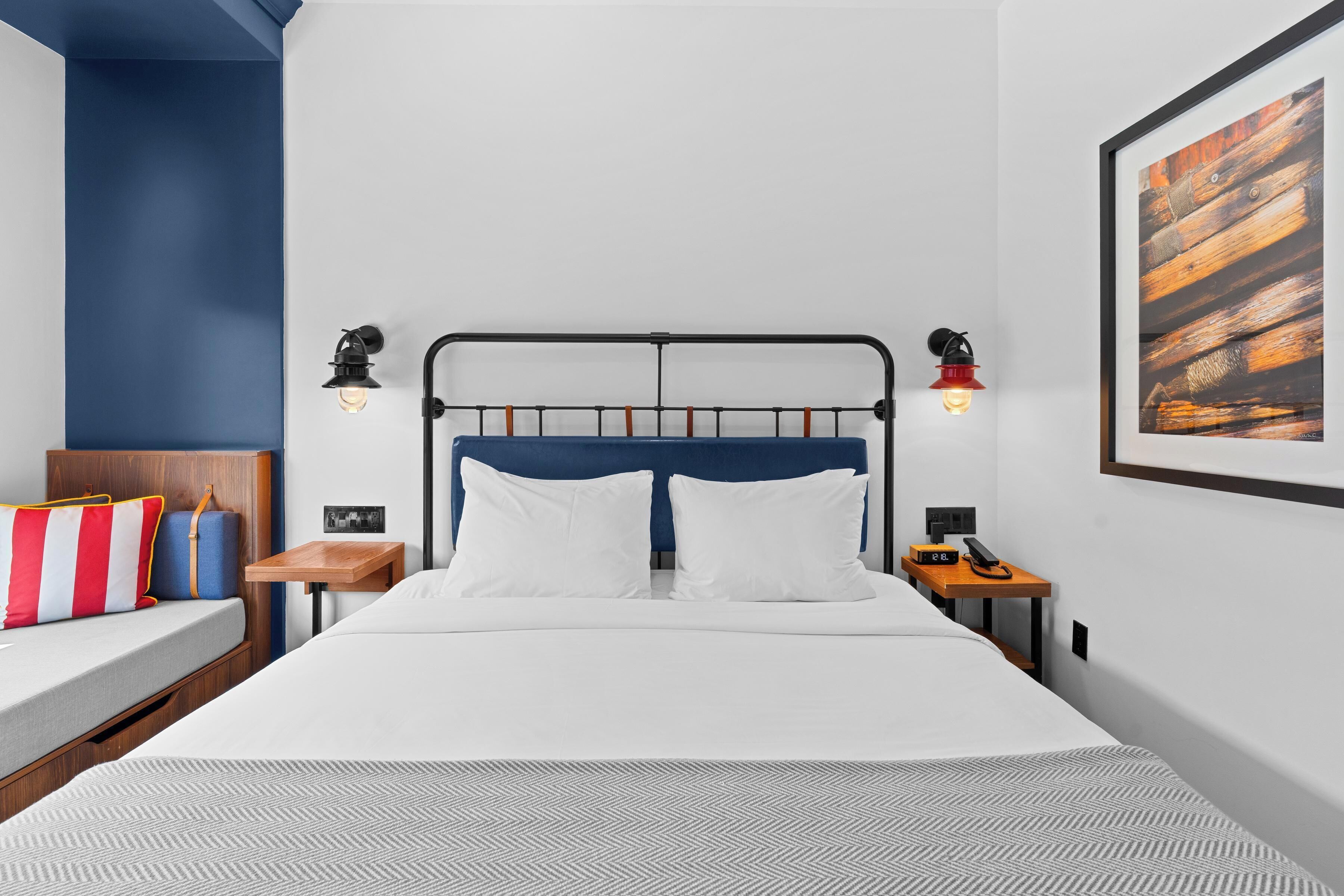Una habitación de hotel moderna con cama, mesitas de noche y una obra de arte colgada en la pared.