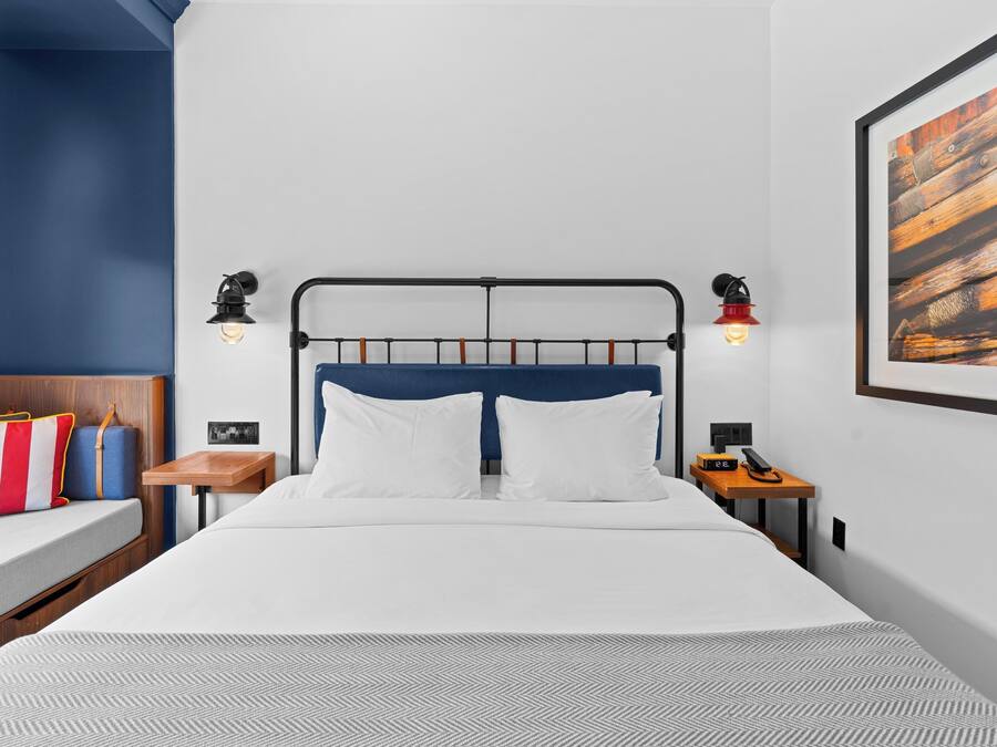 Una habitación de hotel moderna con cama, mesitas de noche y una obra de arte colgada en la pared.