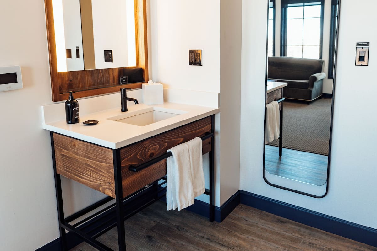 Features a sleek vanity, large mirror, and glass door offering a view of the living area.