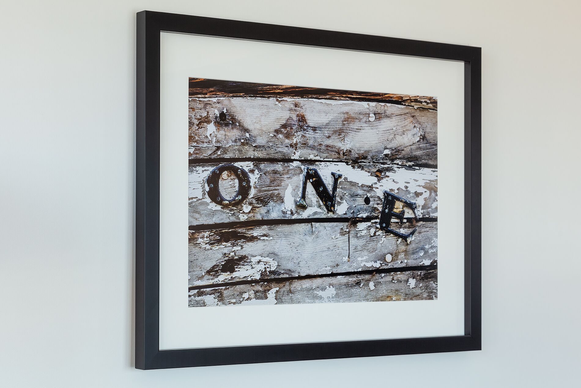 A framed artwork with the word "ONE" on a weathered wooden background.