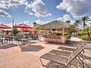 Relax in the hotel's outdoor patio area, featuring a thatched-roof bar and comfortable seating.