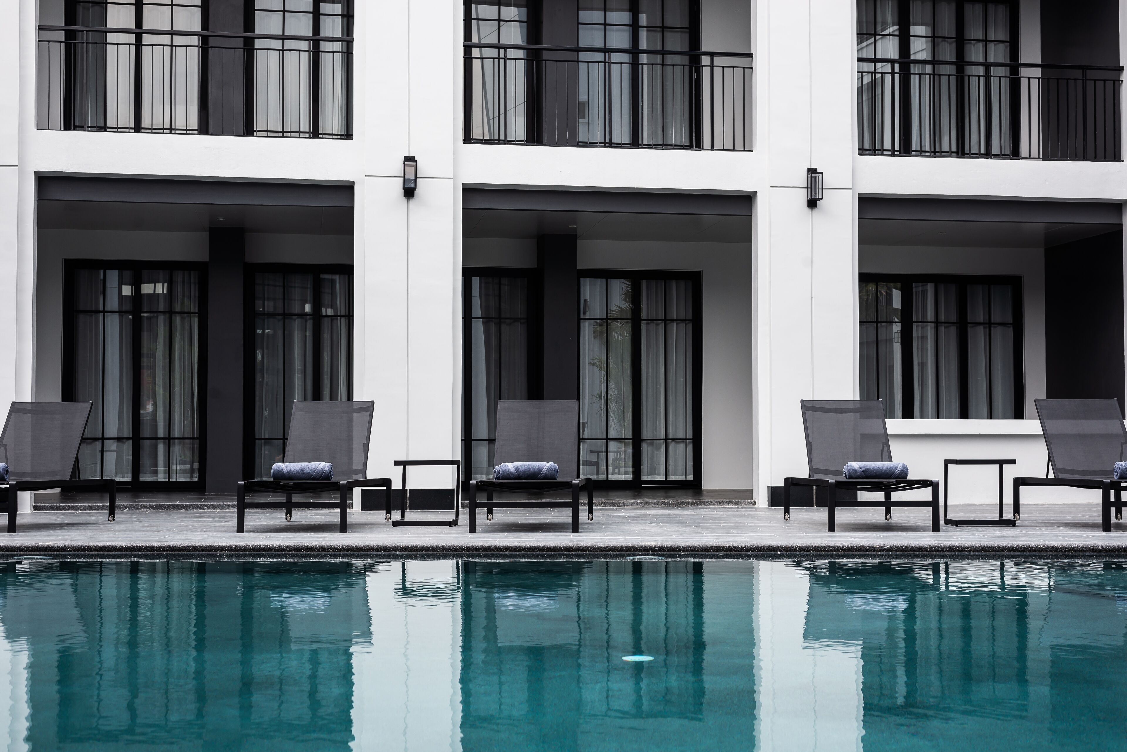 Ein modernes Gebäude mit Poolbereich. Liegestühle und ein Pool sind vorhanden.