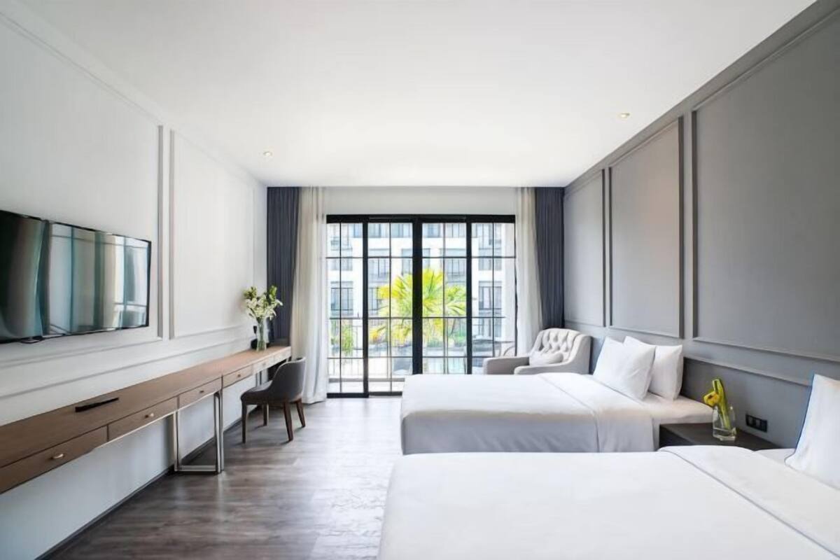 Habitación de hotel con cama, escritorio, silla, televisor y ventana con vista.