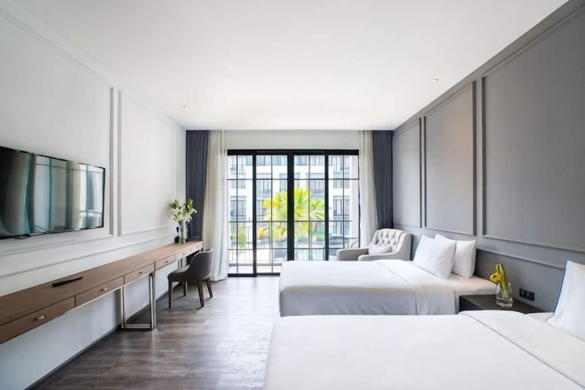 Une chambre d’hôtel équipée d’un lit, d’un bureau, d’une chaise, d’une télévision et d’une fenêtre donnant sur un paysage agréable.