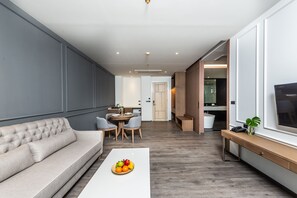 Een moderne woonkamer met een bank, een salontafel met fruit, een eethoek en een tv op een dressoir.