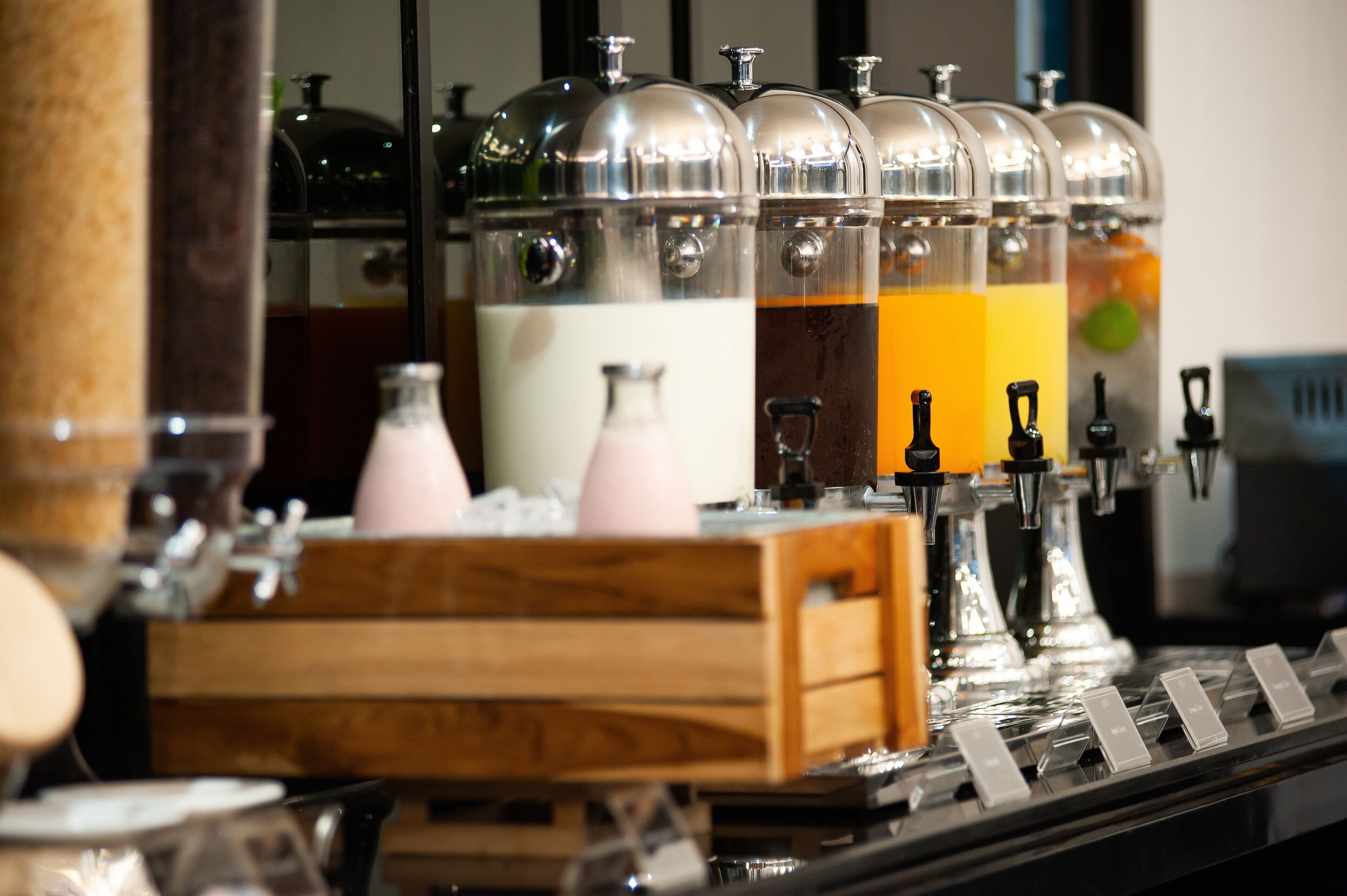 A beverage station with multiple dispensers, each with a different colored liquid, and a wooden crate in the foreground.
