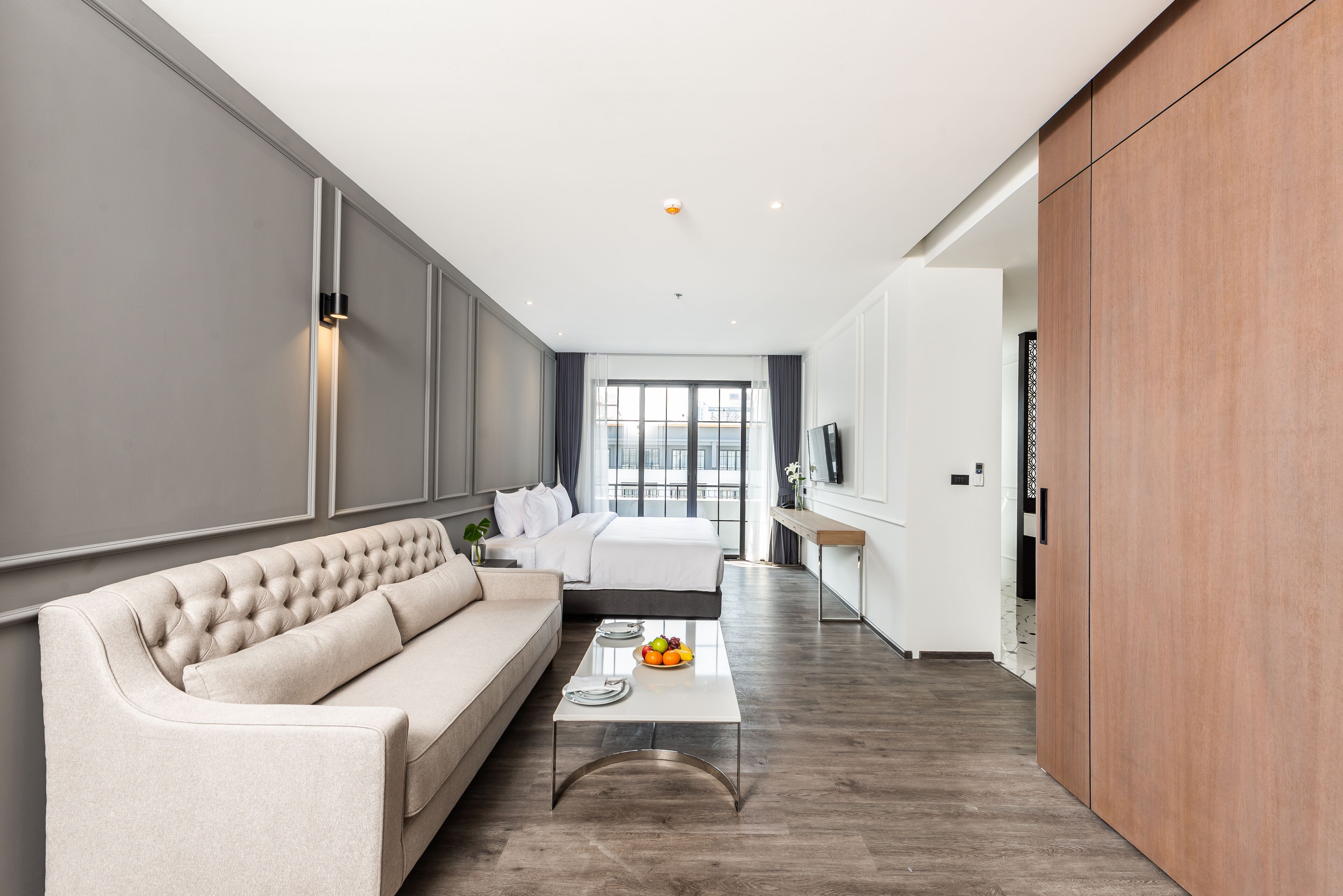 A modern living room with a sofa, a coffee table with fruit, and a TV.