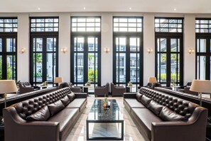 A spacious lobby with leather sofas, a central coffee table, and large windows offering views of the city. - One Patio Hotel Pattaya (Pattaya)