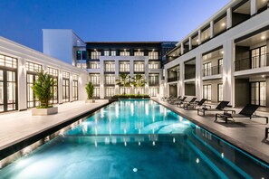 Ein modernes Hotel mit Schwimmbad, mehreren Balkonen und einer gut beleuchteten Fassade.