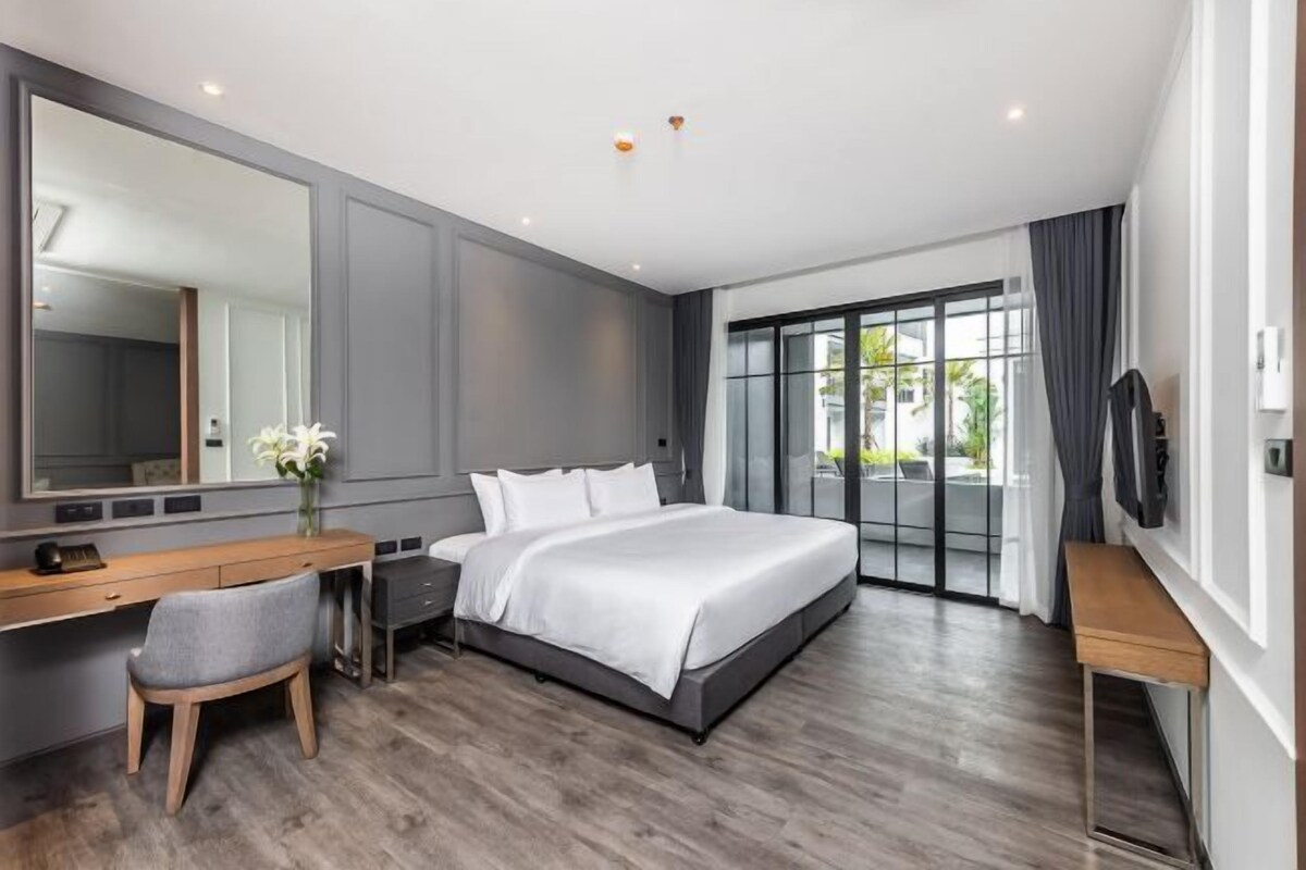 A modern bedroom with a large bed, a desk, and a chair.