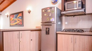 Eine Küche mit Holzausstattung, einem Edelstahlkühlschrank, einer Mikrowelle und einem Gasherd.