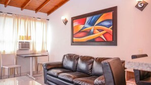 Ein Wohnzimmer mit einer Ledersofa, einem Gemälde an der Wand und einem Tisch mit einer Lampe.