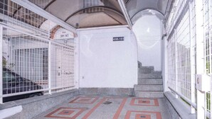 Ein Korridor mit Fliesenboden mit geometrischen Mustern, einer Treppe und Metallgittern.