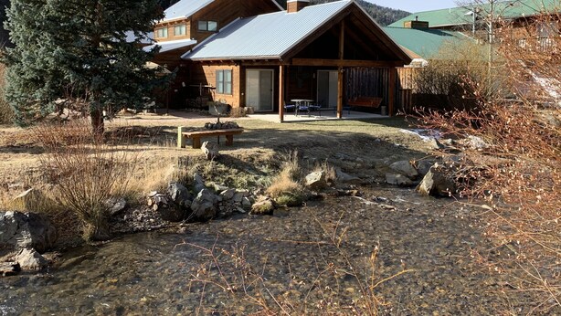 A cabin with a metal roof, wooden exterior, and a stone fireplace.