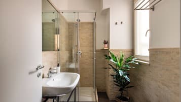 Une salle de bain moderne avec une baignoire sur pieds, une douche à parois de verre et une plante en pot.