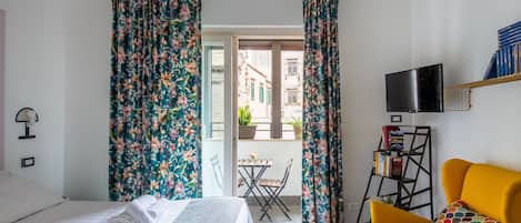 Una habitación de hotel con una cama, un sillón amarillo, un televisor y una estantería.