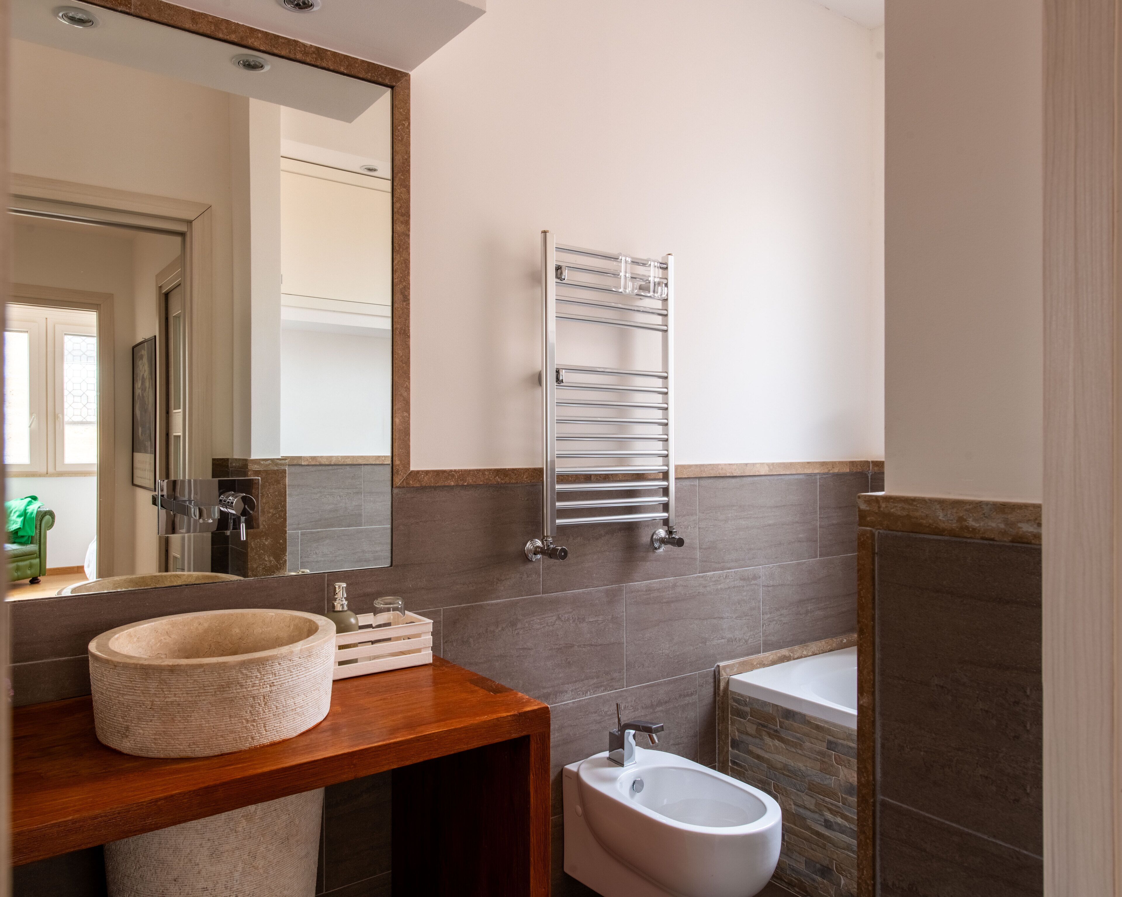 Un baño moderno con tocador de madera, un bidé, un perchero y un espejo grande.