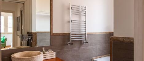 Un baño moderno con tocador de madera, un bidé, un perchero y un espejo grande.