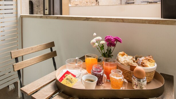 Una bandeja de desayuno con diferentes alimentos y bebidas en un balcón con vista a la ciudad.