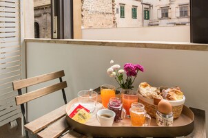Una bandeja de desayuno con diferentes alimentos y bebidas en un balcón con vista a la ciudad.