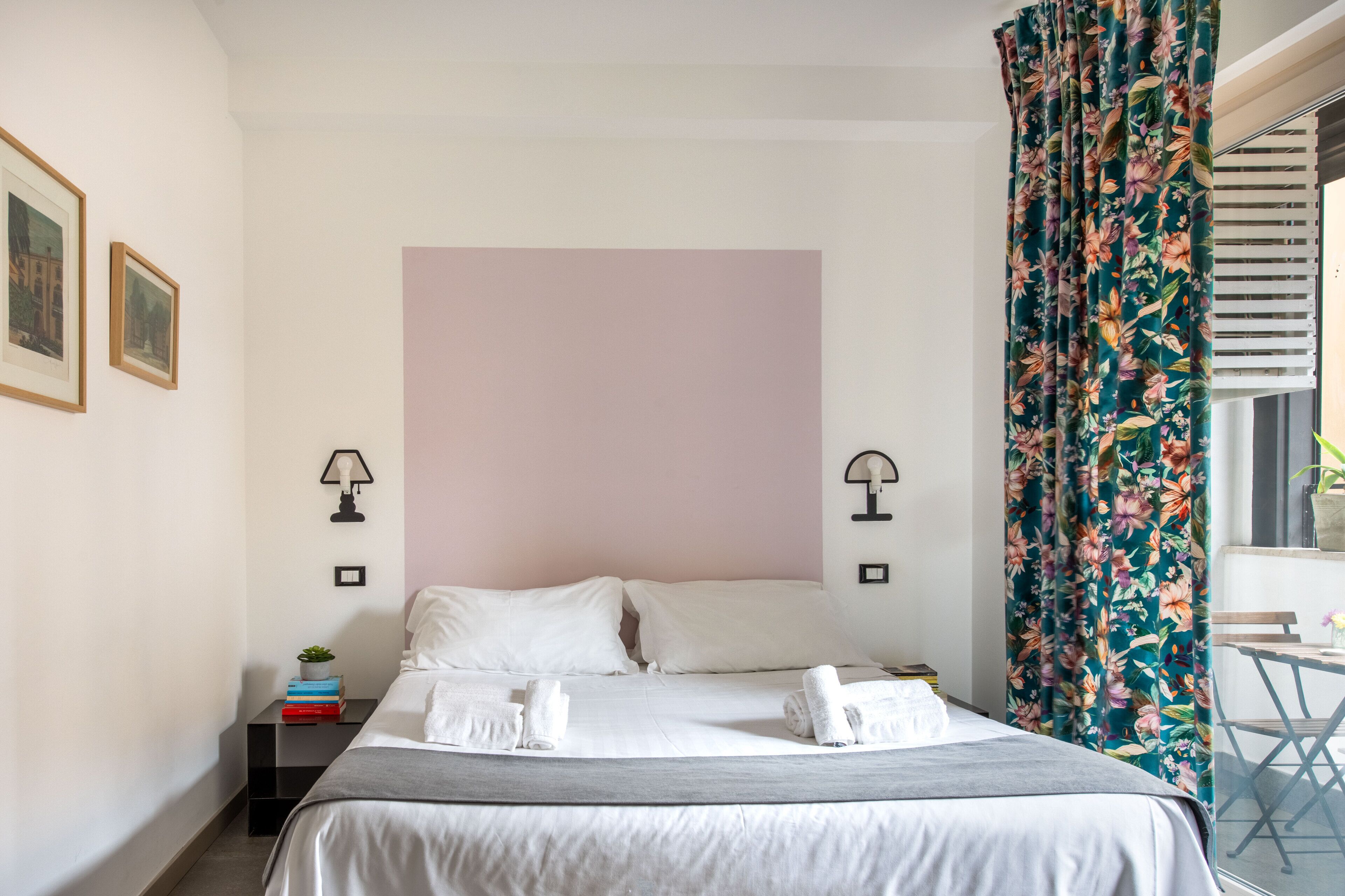 Un dormitorio ordenado con cama, mesitas de noche y ventana con cortinas.