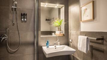 Une salle de bain moderne avec une douche, un lavabo et un miroir.