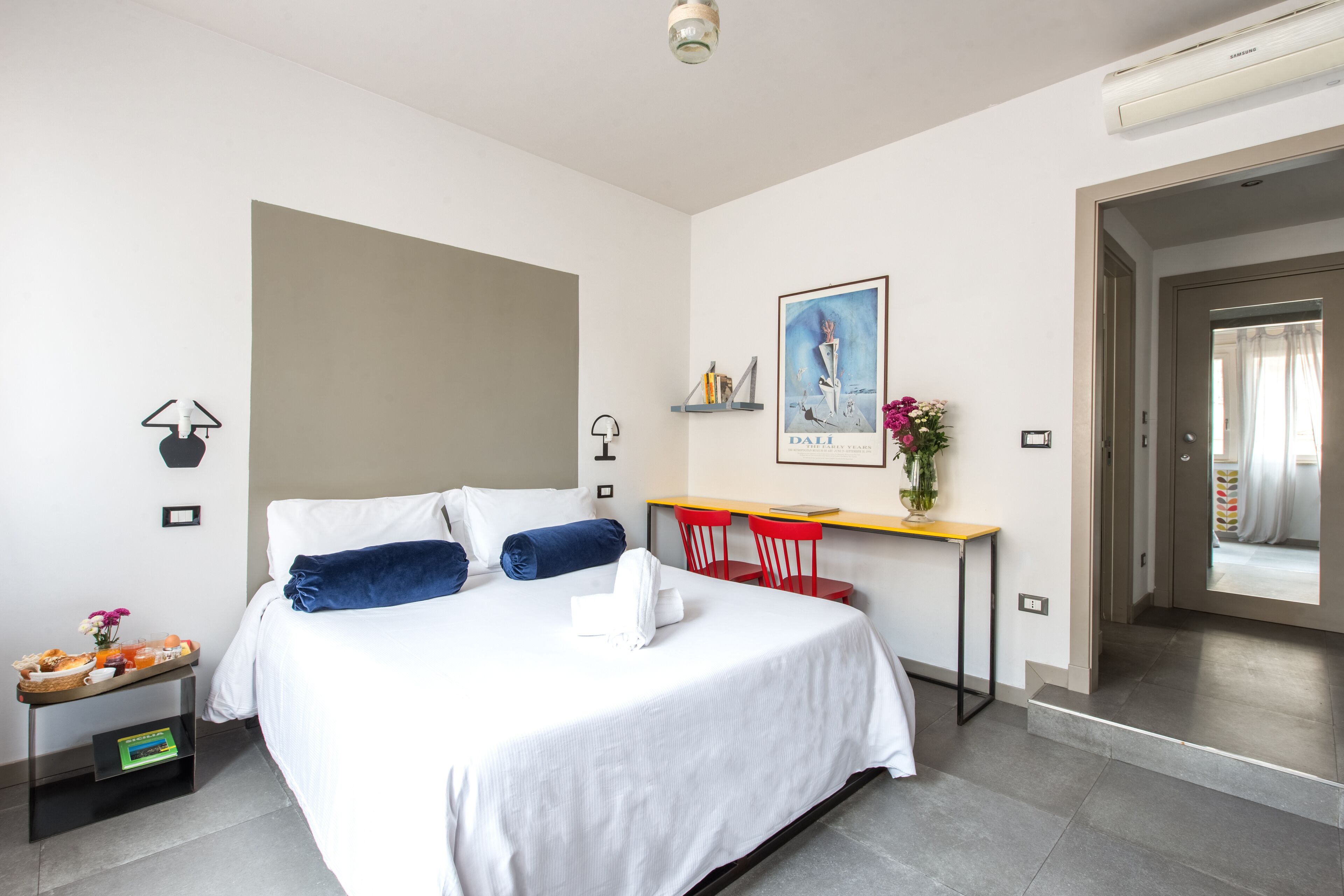 Une chambre d’hôtel avec un lit, une table de chevet et un bureau avec des chaises.