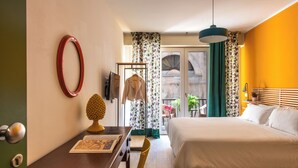Una habitación de hotel con cama, escritorio, silla, perchero y puerta.