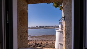 A view through a window with a stone wall, a white railing, and a clear sky.