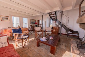 A spacious living area with a wooden table, chairs, a staircase, and a view of the outside.