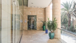 Un vestíbulo de hotel con pared de piedra, puerta de cristal y plantas en macetas.