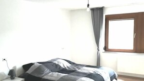 A bedroom with a bed, a nightstand, a window with curtains, and a light fixture. - FeWo BC 40 (Stuttgart)