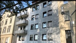 A multi-story building with a modern facade, several balconies, and a parking area with cars. - FeWo BC 40 (Stuttgart)