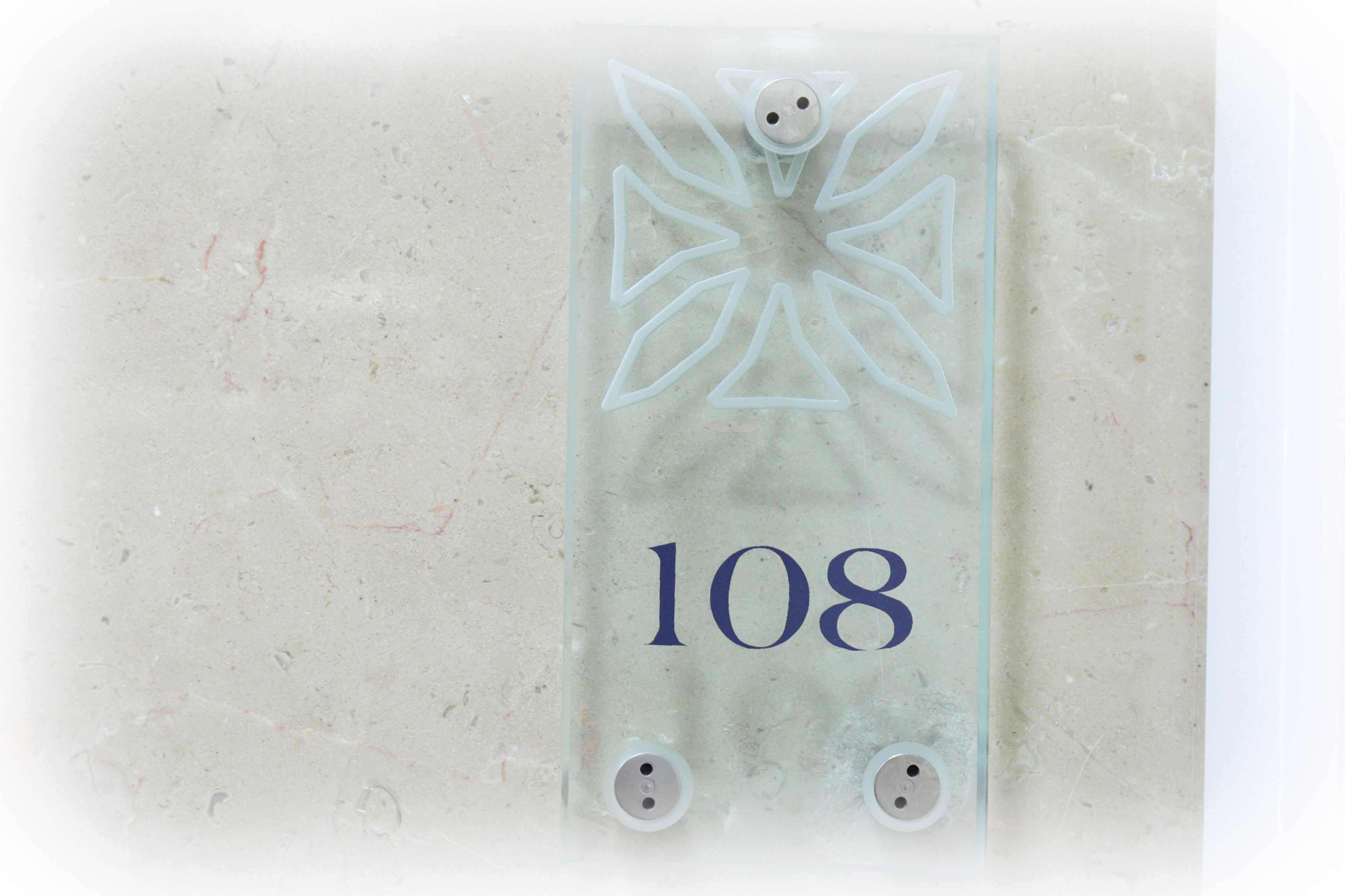 A clear glass sign with the number 108, indicating a room or location.