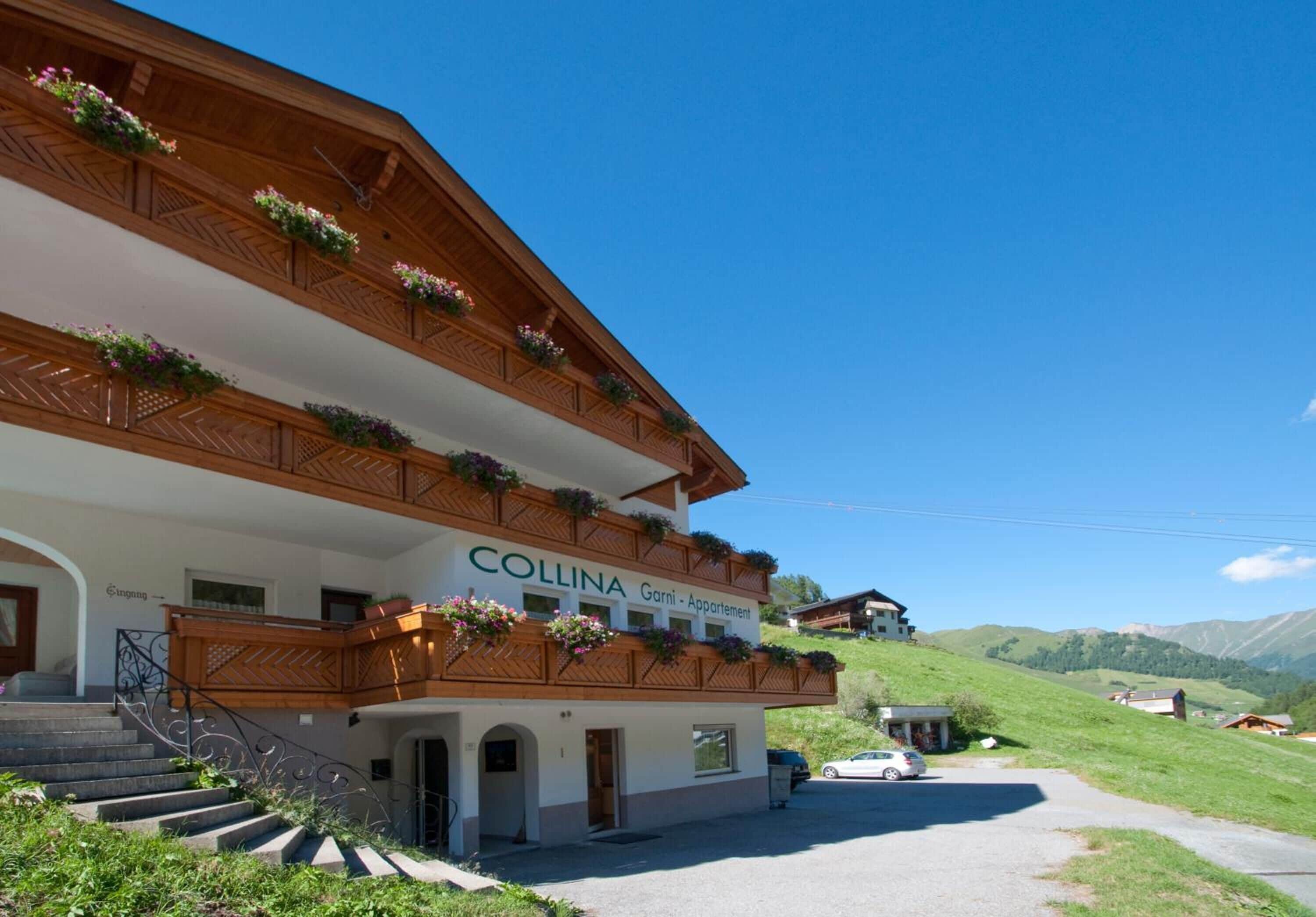A multi-story building with balconies adorned with flowers, labeled "Collina Garni - Appartement."