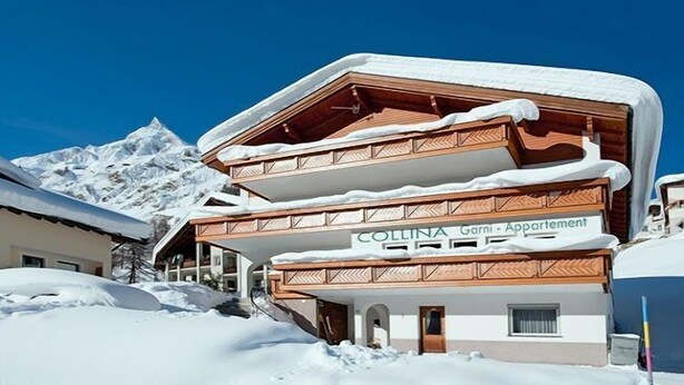 A multi-story building with a snow-covered roof and a sign that reads "COLLINA Garni - Apartment". - Garni Appartement Collina (Samnaun)