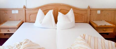 A double bed with a wooden headboard, two bedside tables, and striped bedspreads.