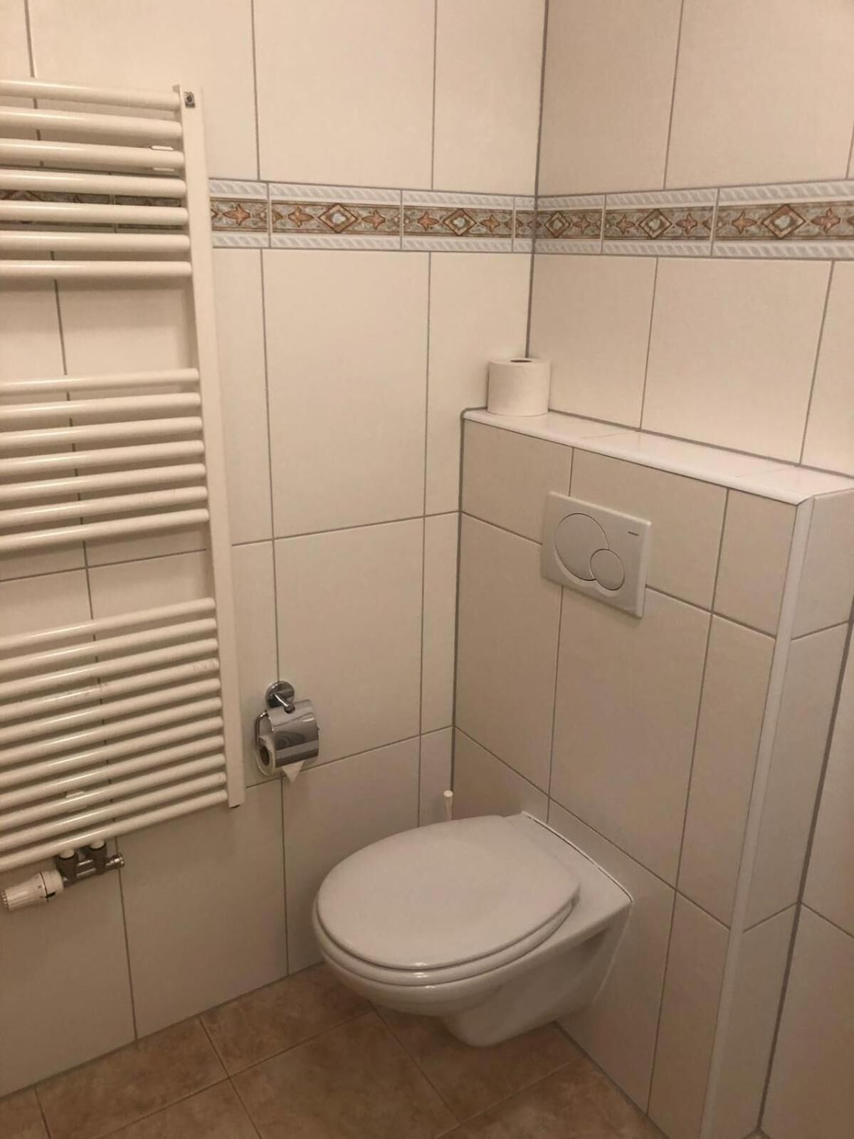 A small, clean bathroom with a toilet, a towel rack, and a toilet paper holder.
