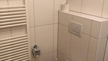 A small, clean bathroom with a toilet, a towel rack, and a toilet paper holder.