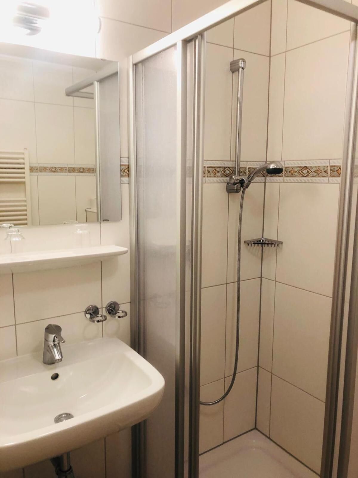A bathroom with a glass-enclosed shower, a white sink, and a mirror above the sink.