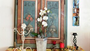A vintage wooden cabinet with decorative panels, a vase with white flowers, and a small angel figurine. - Garni Appartement Collina (Samnaun)