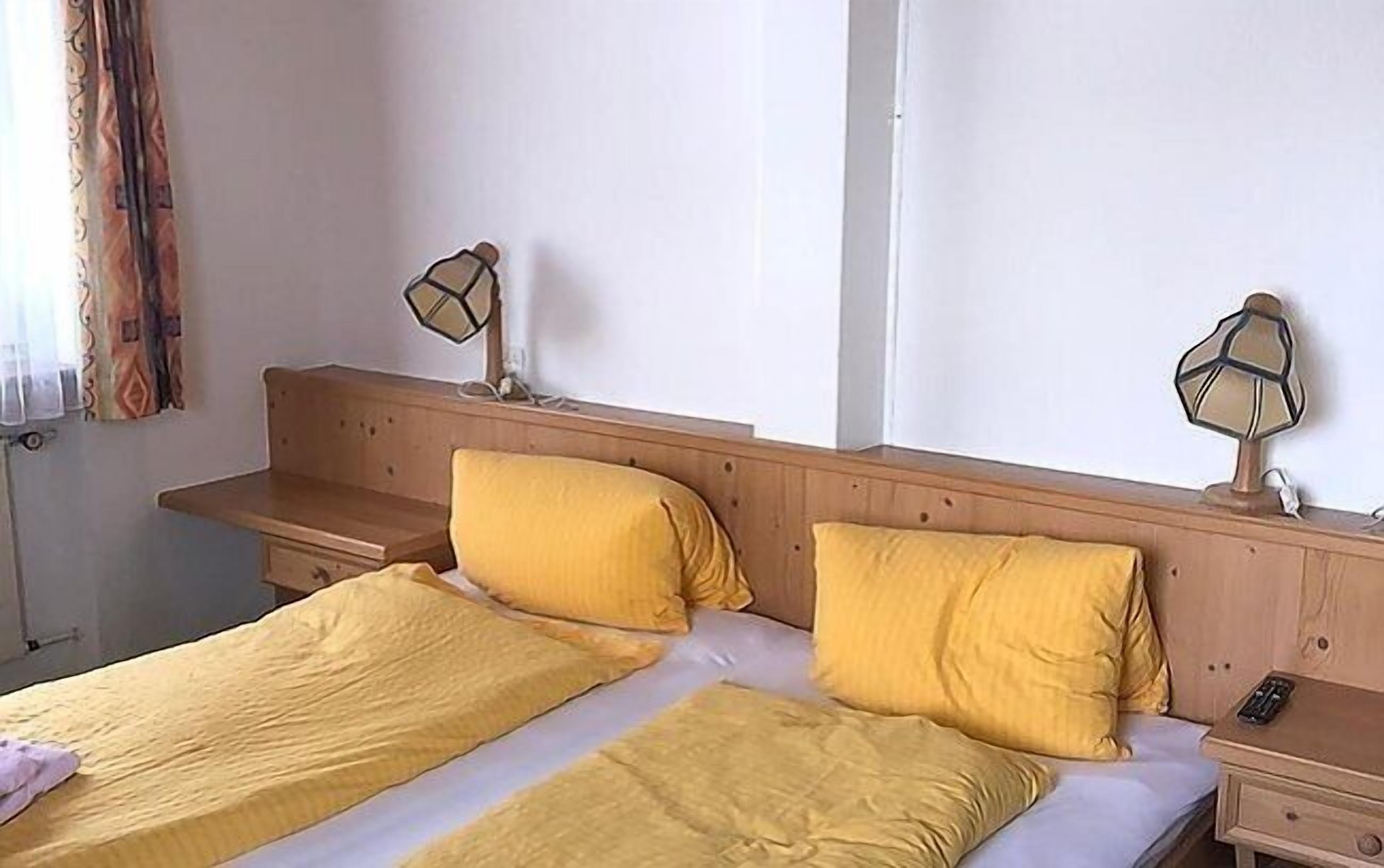 Una cama doble con ropa de cama amarilla y dos lámparas de noche.