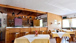 A restaurant with wooden interiors, a bar area, and tables set for dining. - Garni Appartement Collina (Samnaun)