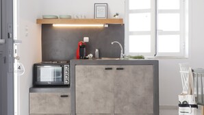 A compact kitchen with a built-in microwave, a coffee maker, and a sink. - Galini Rooms & Apartments Syros (Syros)