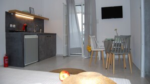 A modern kitchen with a built-in fridge, a coffee machine, and a small dining area with a table and chairs. - Galini Rooms & Apartments Syros (Syros)